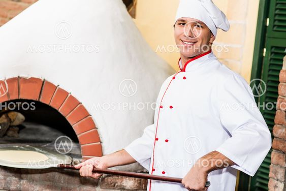 Køkkenchefen sætter dejen i ovnen til pizzaer,