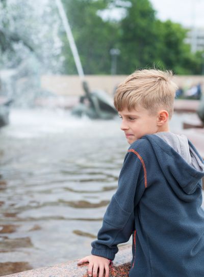 Blonde boy standing at a fountain