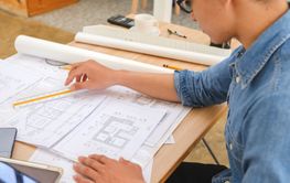 Architect and engineer analyzing blueprints at a work...