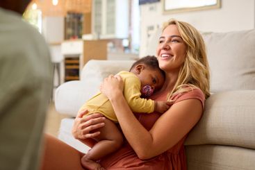 Family Shot With Parents Cuddling Baby Daughter Sitting...