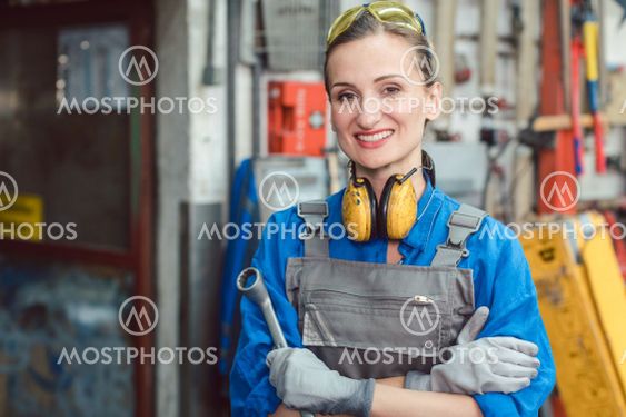Woman worker in her metal workshop posing with tools