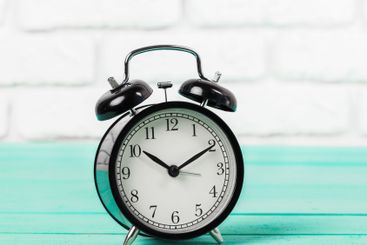Black vintage alarm clock on wooden table