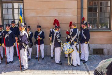 Soldiers in historical Swedish military uniforms with flag
