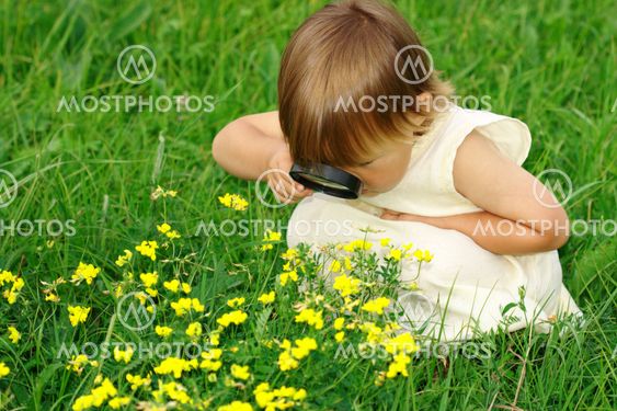 Child looking at flowers through magnifying glass