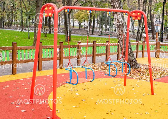 Children's playground with a swing in the autumn park.