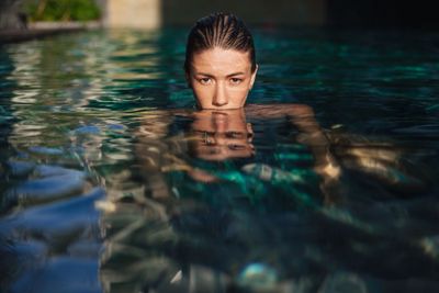 beautiful young woman immersed in water at swimming pool...