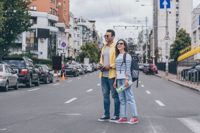 Woman holding map and standing on road near bi-racial...