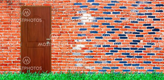 door on old brick wall with verdant grass & bright sky