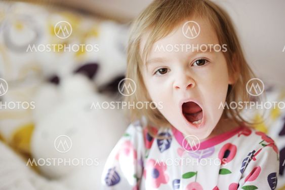 Little yawning girl in pajamas on sunny morning