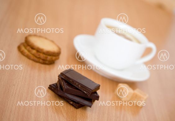 Cup of black tea with lemon, sugar, biscuits and chocolate. Focus on chocolate