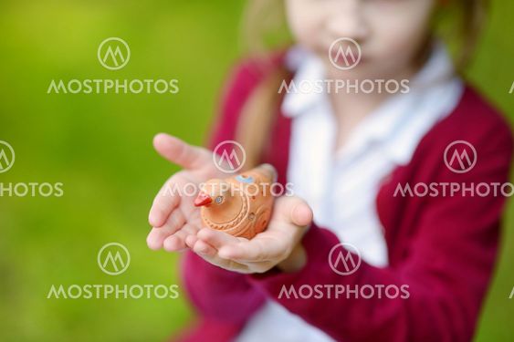 Adorable girl holding clay whistle
