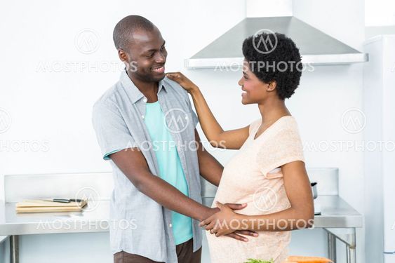 Pregnant couple cuddling in kitchen