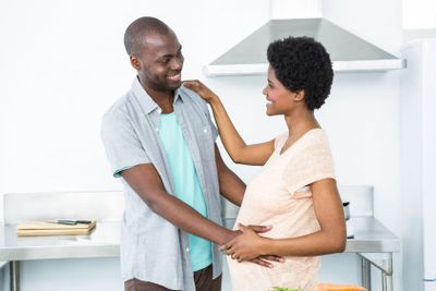 Pregnant couple cuddling in kitchen
