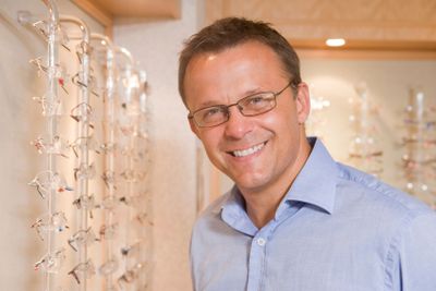 Man trying on eyeglasses at optometrists smiling