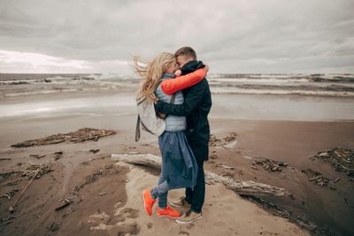 happy young couple hugging on seashore in Riga 