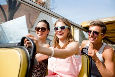 group of smiling friends traveling by tour bus