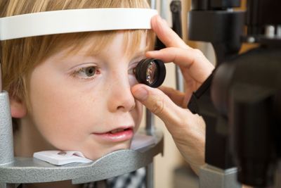 Optician's Hand Examining Boy's Retina