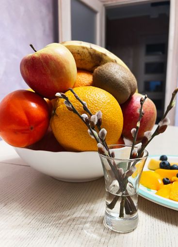 Fruit bowl and willow branches arranged on a wooden...