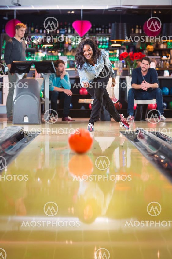 woman plays bowling and throws a ball