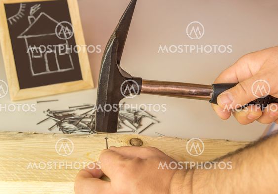 Mans hand hammering nail in wood