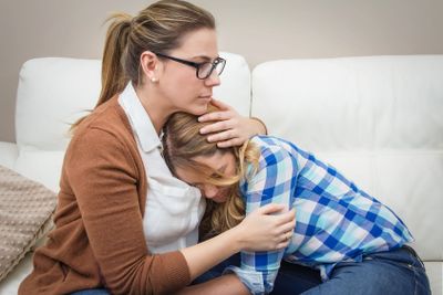Mother embracing and soothes depressed daughter