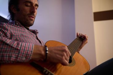 Man playing an acoustic guitar in a relaxed indoor setting