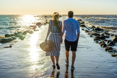 back view of couple in love walking on seashore during...