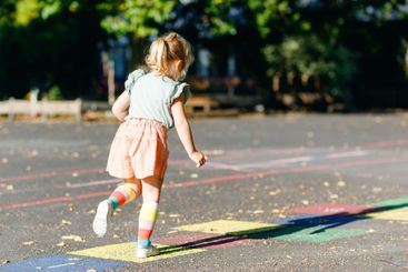 Cute little toddler girl playing hopscotch game drawn...