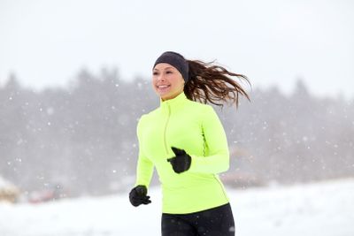 happy woman running along snow covered winter road