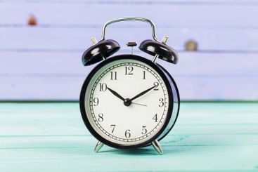Black vintage alarm clock on wooden table
