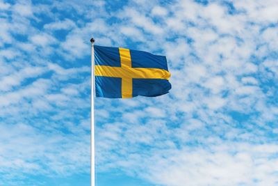 Swedish flag waving in wind against a blue sky