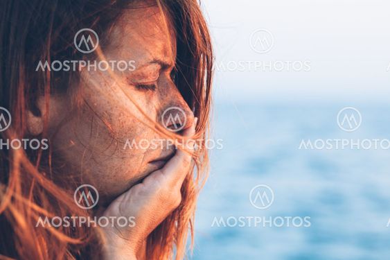 Young woman feeling sad by the sea