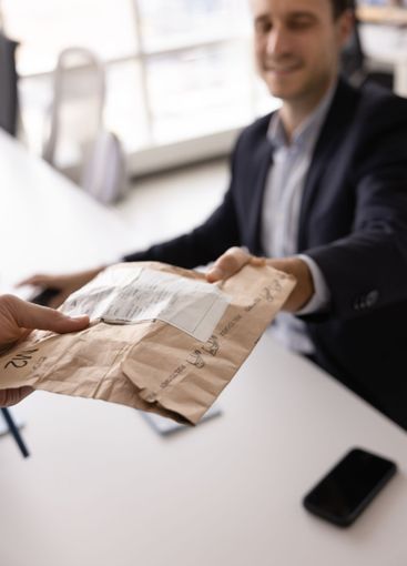 Male Internet store manager giving packet to customer