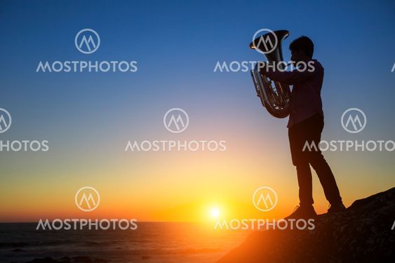 Silhouette of musician play Tuba on sea beach at magical...