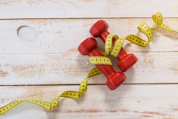 Fitness concept with dumbbells and measuring tape