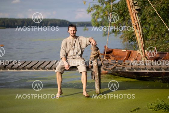 Young viking near the drakkar on the lake