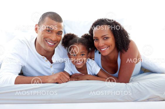 Affectionate parents and their daughter smiling at the camera