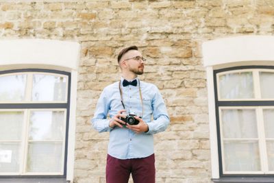 young hipster man with film camera in city