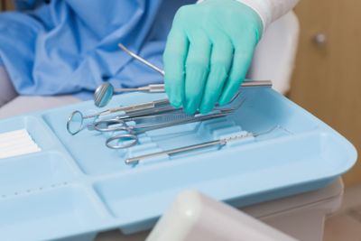 Dentist in blue scrubs picking up tools