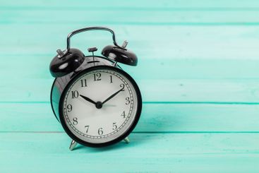Black vintage alarm clock on wooden table