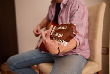 Person playing an acoustic guitar indoors in a relaxed...