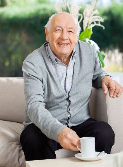 Happy Senior Man Having Coffee At Nursing Home Porch