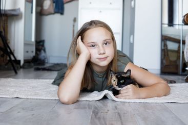 Smiling little girl with cat indoor. Child and pet together