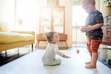 Baby, living room and children play with toys for...