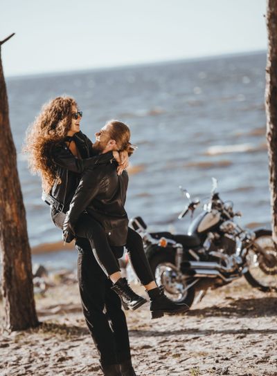 couple having fun on seashore with chopper motorcycle near