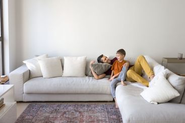 Dad and little son spending time together on spacious sofa