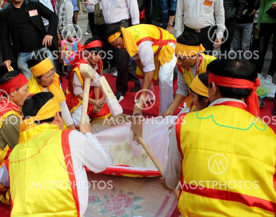 People in traditional costume exam to make round sticky...