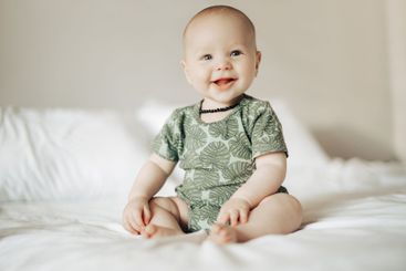 Baby boy, bed and happy in home with excited face,...