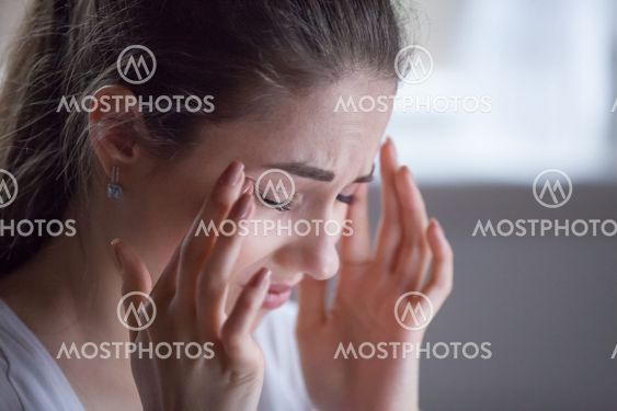 Close up of exhausted female suffering from headache