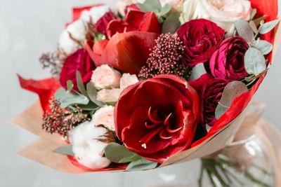beautiful bouquet of mixed flowers into a vase on wooden...